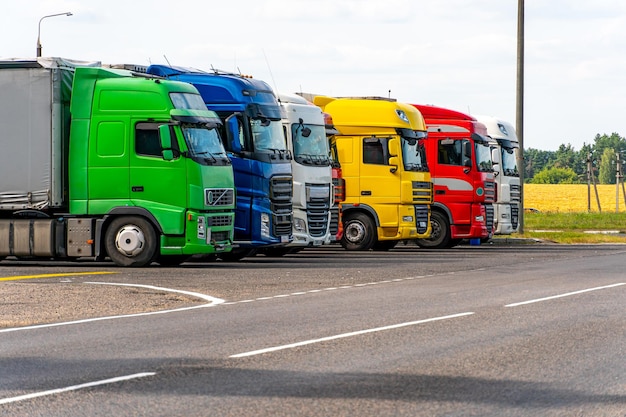 Foto camiones con contenedores en el estacionamiento a lo largo de la carretera contra el fondo de las nubes el concepto de transporte logístico y transporte de carga el lugar de descanso de los camiones en el estacionamiento