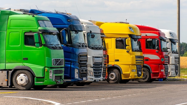 Foto camiones con contenedores en el estacionamiento a lo largo de la carretera contra el fondo de las nubes el concepto de transporte logístico y transporte de carga el lugar de descanso de los camiones en el estacionamiento