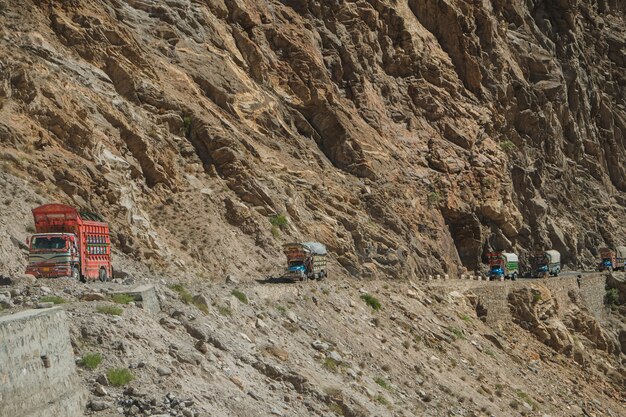 Camiones paquistaníes que viajan por una carretera pavimentada a lo largo de la montaña cerca del acantilado en la carretera Karakoram.