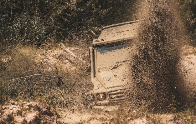 Camioneta deportiva todoterreno entre paisajes montañosos Mudding es todoterreno a través de un área de barro húmedo o arcilla Salpicaduras de barro y agua en carreras todoterreno Viajes en 4x4 trekking