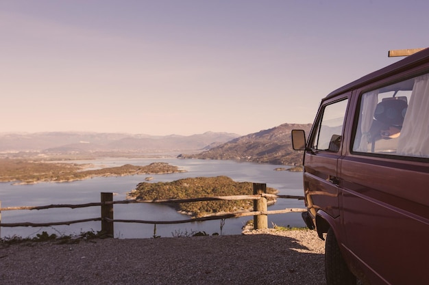 Una camioneta roja está estacionada en una montaña con vista a un lago y un lago.