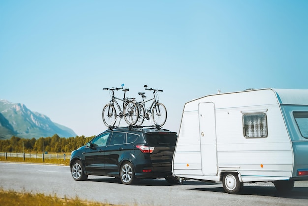 camioneta SUV con bicicletas en el techo y remolque RV viaje por carretera familiar