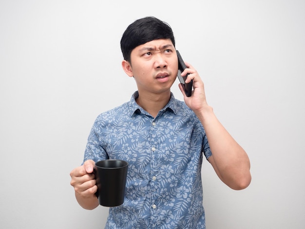 Camisa azul de homem falando com telefone celular e segurando a emoção de raiva de xícara de café