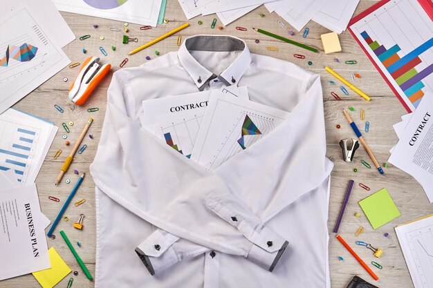 Camisa blanca de vista superior con cosas de escritorio de papelería