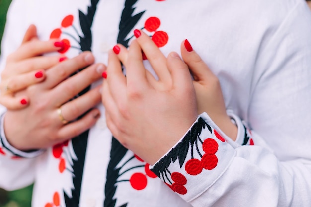 Camisa bordada y manos de recién casados el novio con anillo en