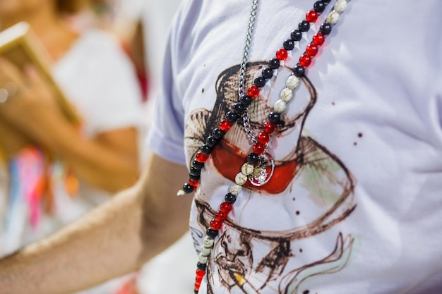 Foto camisa branca com desenho malandro e guias de umbanda vermelha e branca durante o carnaval carioca