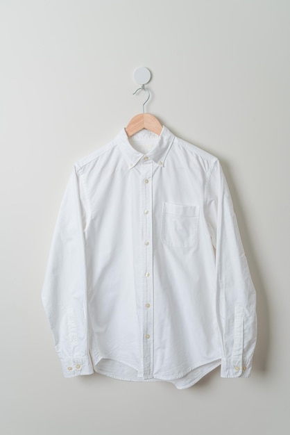 camisa branca pendurada com cabide de madeira na parede