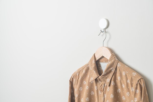 Foto camisa colgante con colgador de madera en la pared