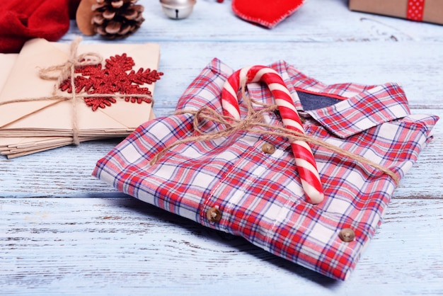 Camisa a cuadros con regalos de Navidad sobre fondo blanco de madera, cerrar