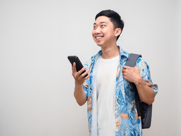 Camisa de praia de homem positivo com mochila segura celular e reserva para viajar de férias