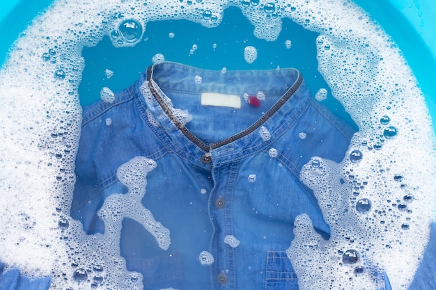 Foto camisa jean empapada en detergente en polvo, disolución de agua, paño de lavado.