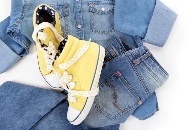 Camisa jeans azul e jeans com tênis amarelos em fundo branco