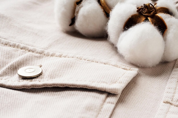 Camisa jeans bege e flores de algodão close-up flat lay top view Conceito de tecidos de algodão duráveis naturais Fundo de roupas casuais confortáveis Tecidos feitos de materiais reciclados
