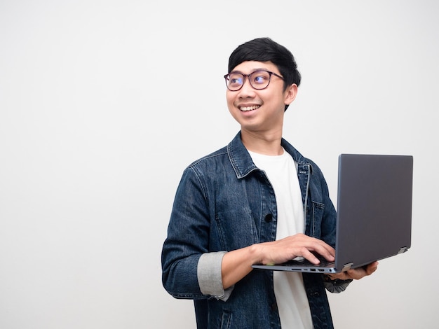 Camisa de jeans de hombre alegre usando la computadora portátil girando la cara mirando el espacio de copia aislado