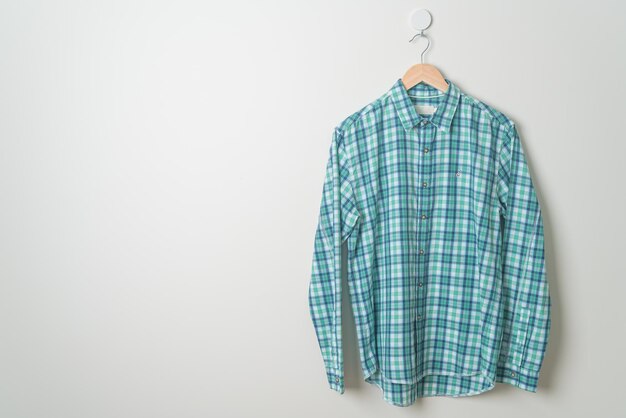 camisa listrada pendurada com cabide de madeira na parede