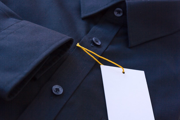 Camisa masculina escura com etiqueta de preço e cordão amarelo-laranja