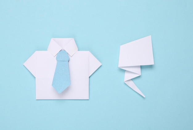 Camisa de origami con corbata y nube de diálogo sobre fondo azul Concepto de negocio