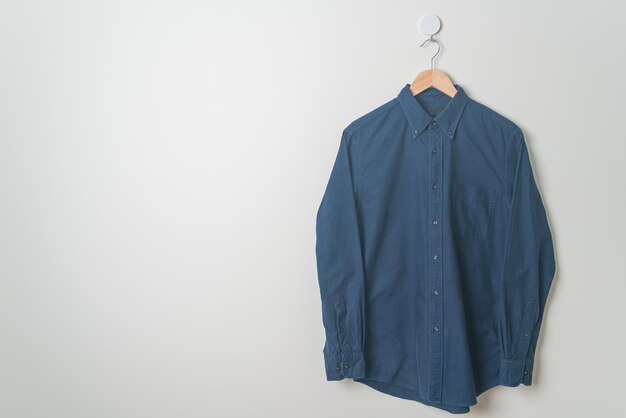 camisa pendurada com cabide de madeira na parede