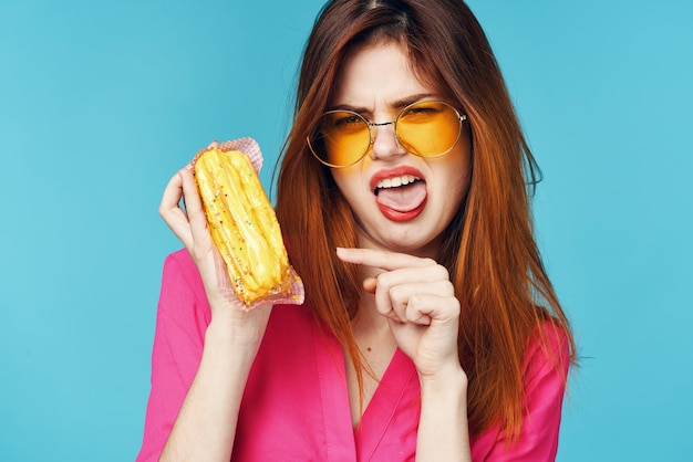 Camisa rosa mulher glamorosa com éclairs nas mãos de doces