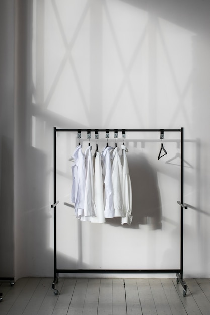 Camisas blancas colgadas en el riel del perchero en un interior minimalista y luminoso moderno.