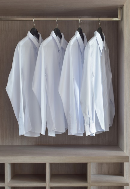 Camisas clásicas blancas en cálido armario de madera.