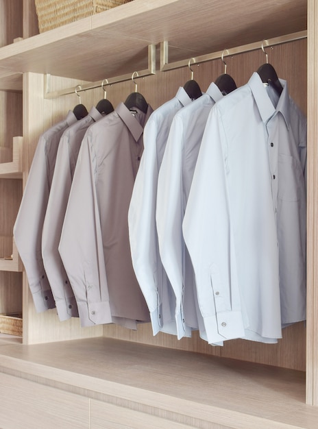 Camisas clásicas de colores colgadas en el cálido armario de madera.