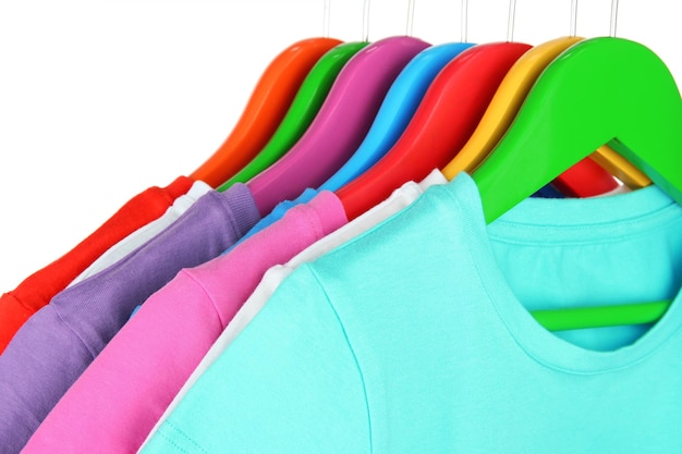 Camisas diferentes en perchas de colores sobre fondo blanco.