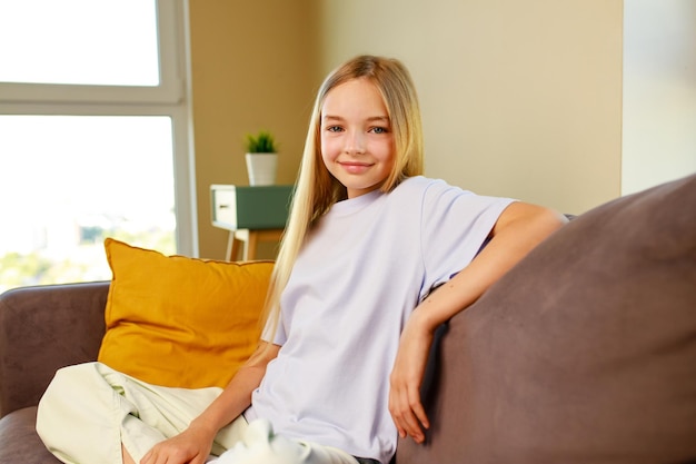 Una camiseta de algodón adolescente feliz sentada en un sofá en casa