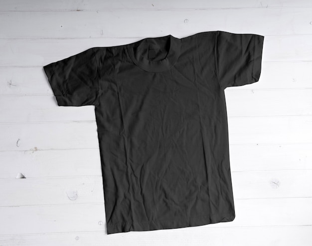 Camiseta de algodón negro sobre fondo blanco de madera