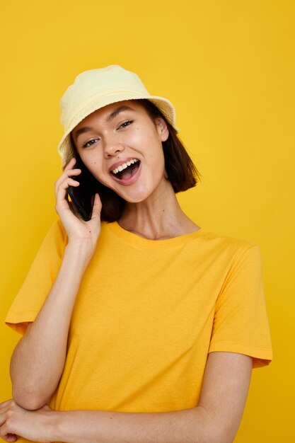 Camiseta amarela de mulher atraente e estilo de verão de chapéu com fundo isolado de telefone