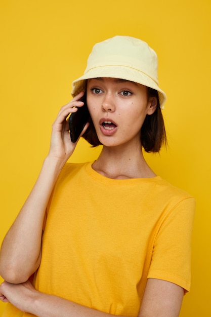 Camiseta amarela de mulher atraente e estilo de verão de chapéu com fundo isolado de telefone