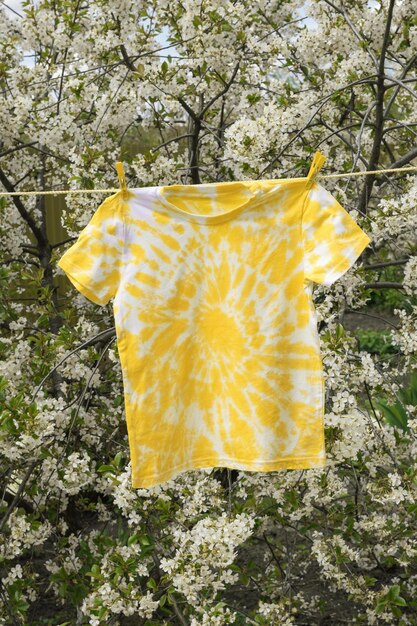 Camiseta amarela pintada à mão em estilo tie dye no fundo das flores de cerejeira