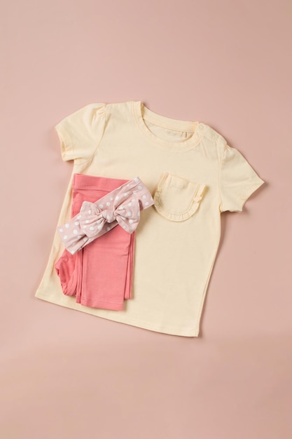 Camiseta amarilla para niños y pantalón rosa doblado sobre un fondo rosa Imagen de moda para una niña