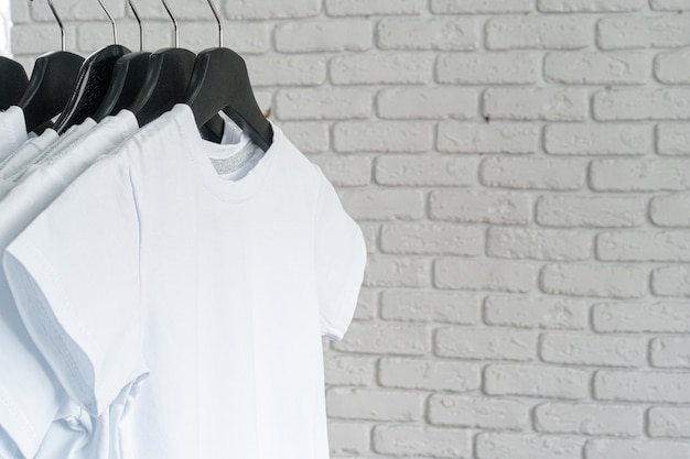 Foto camiseta blanca colgada en la percha contra la pared de ladrillo, espacio de copia