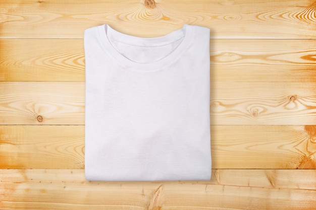 Camiseta blanca doblada en blanco sobre fondo blanco de madera