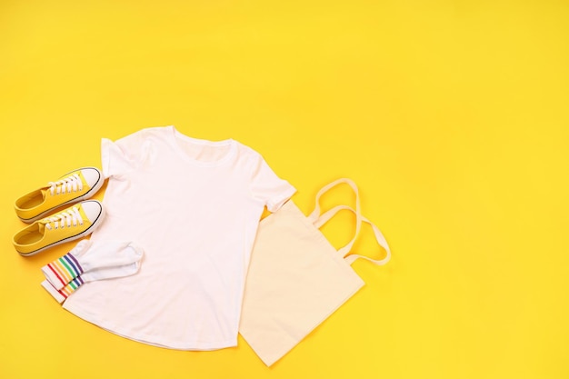 Camiseta, bolsa, meias e tênis em branco sobre fundo amarelo