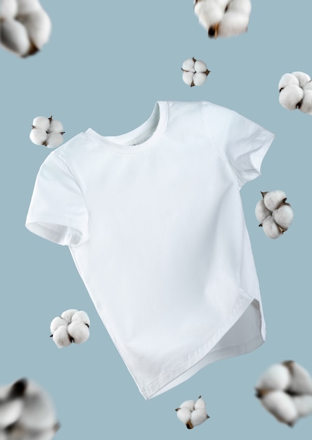 Camiseta branca de algodão voadora isolada sobre fundo azul. T-shirt branca limpa para mulheres ou homens. Unissex. flores de algodão. Vista frontal de roupas de marca. Mock up para o seu design. Camiseta Básica Branca Clássica