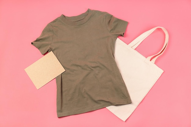 Camiseta em branco, bolsa e folha de papelão em fundo rosa