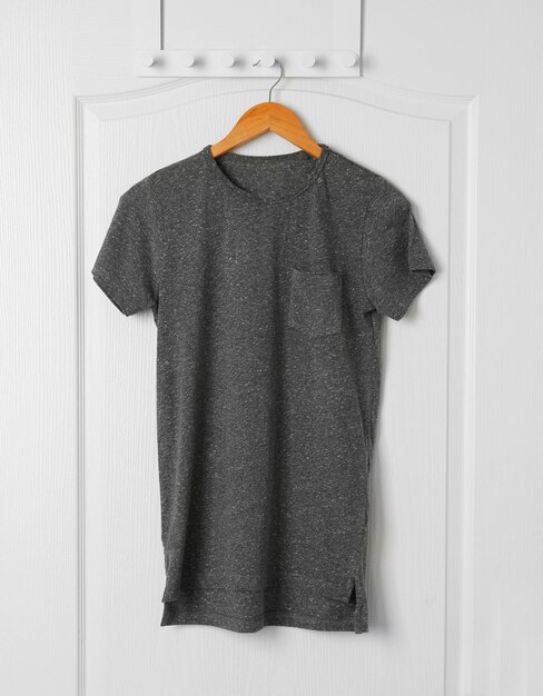 Camiseta gris en blanco colgada en la puerta blanca
