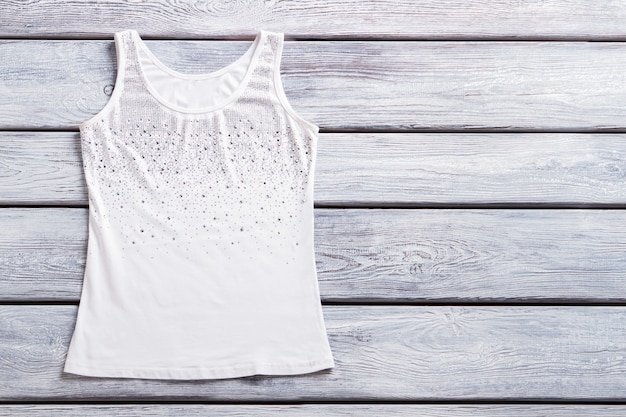Camiseta sin mangas con diamantes de imitación, ropa de verano con top casual blanca para dama, en un estante de madera, artículo vendido en una tienda de moda