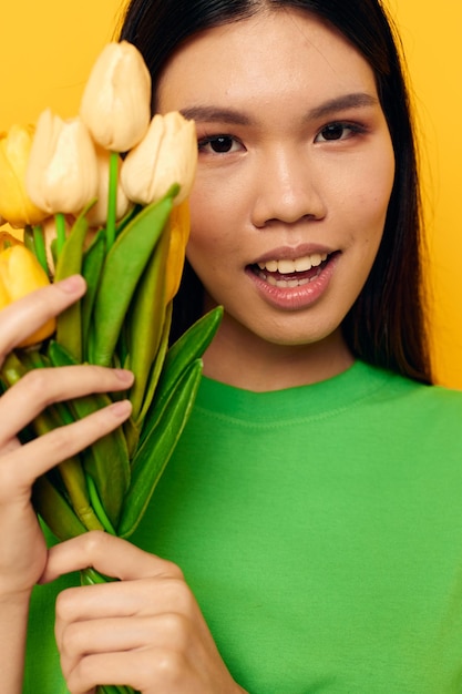 camiseta mujer verde un ramo de flores amarillas fondo amarillo inalterado. foto de alta calidad