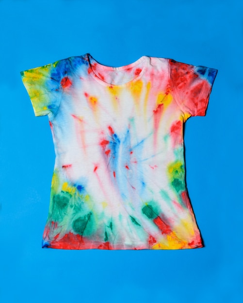 Camiseta pintada en estilo tie dye sobre fondo azul.