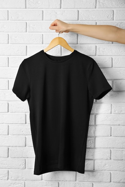 Camiseta preta em branco contra a parede de tijolos