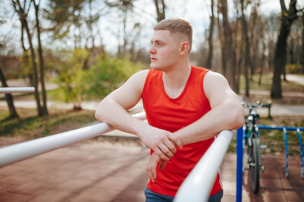 Camiseta roja y ropa deportiva en un joven atleta Un retrato de fuerza y estilo al aire libre Retrato de un joven elegante en auténtica ropa deportiva roja Un modelo de juventud y confianza al aire libre