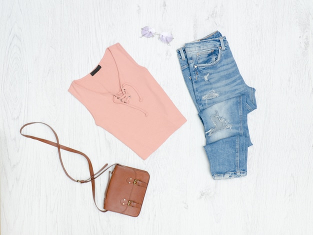 Camiseta rosa, jeans rotos, bolso y gafas de sol. Concepto de moda