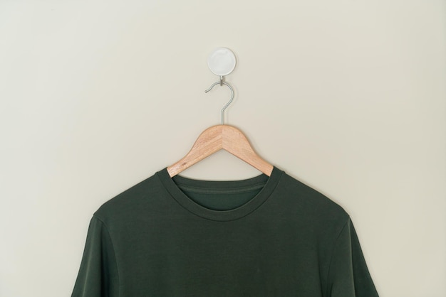 camiseta verde oscuro colgada con un colgador de madera en la pared