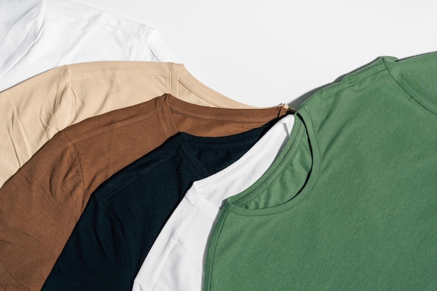 Camisetas blancas beige y verdes dispuestas sobre un fondo blanco aislado El concepto de elegir ropa y reemplazar el guardarropa