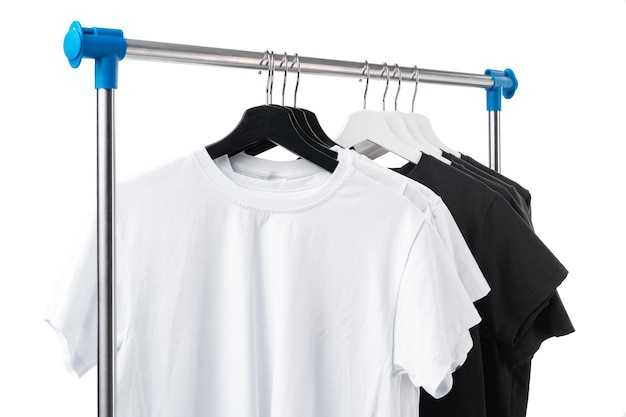 Camisetas blancas y negras en perchas en un estante de metal aislado en blanco