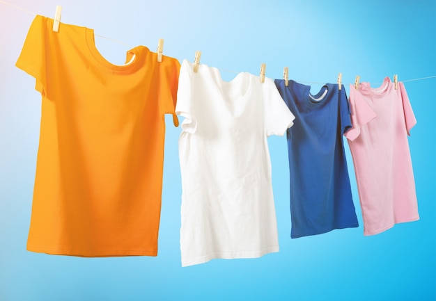 Camisetas coloridas penduradas em uma corda em um fundo branco