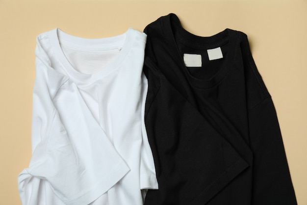 Camisetas pretas e brancas na superfície bege